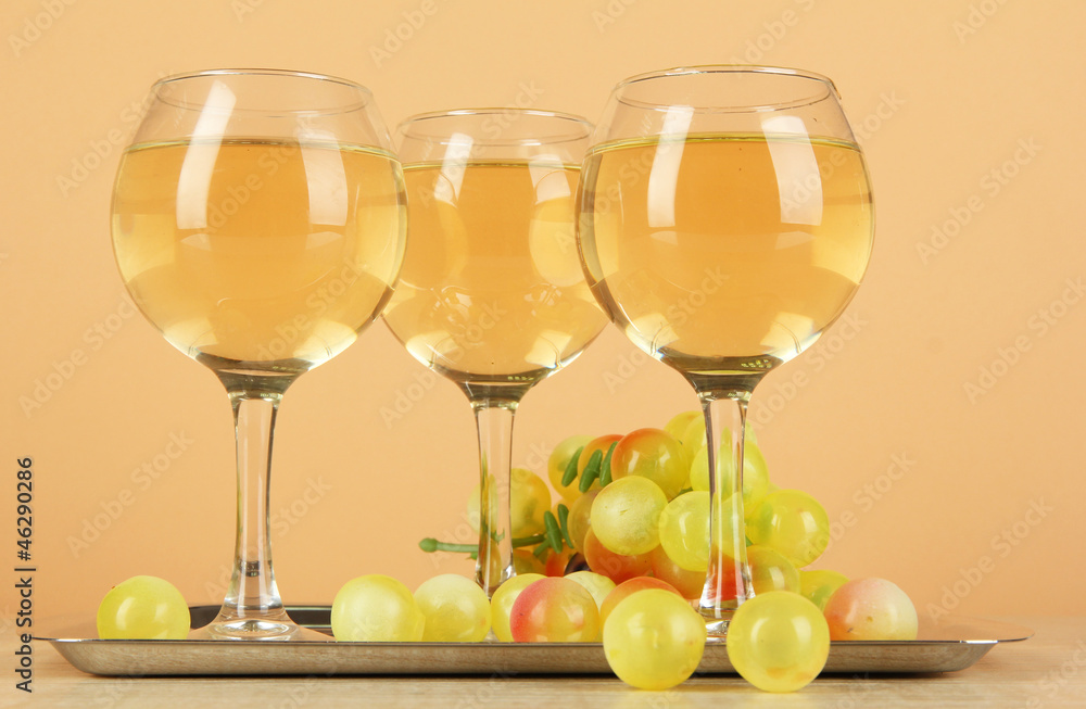 White wine in glass on salver on beige background White wine in glass on salver on beige background