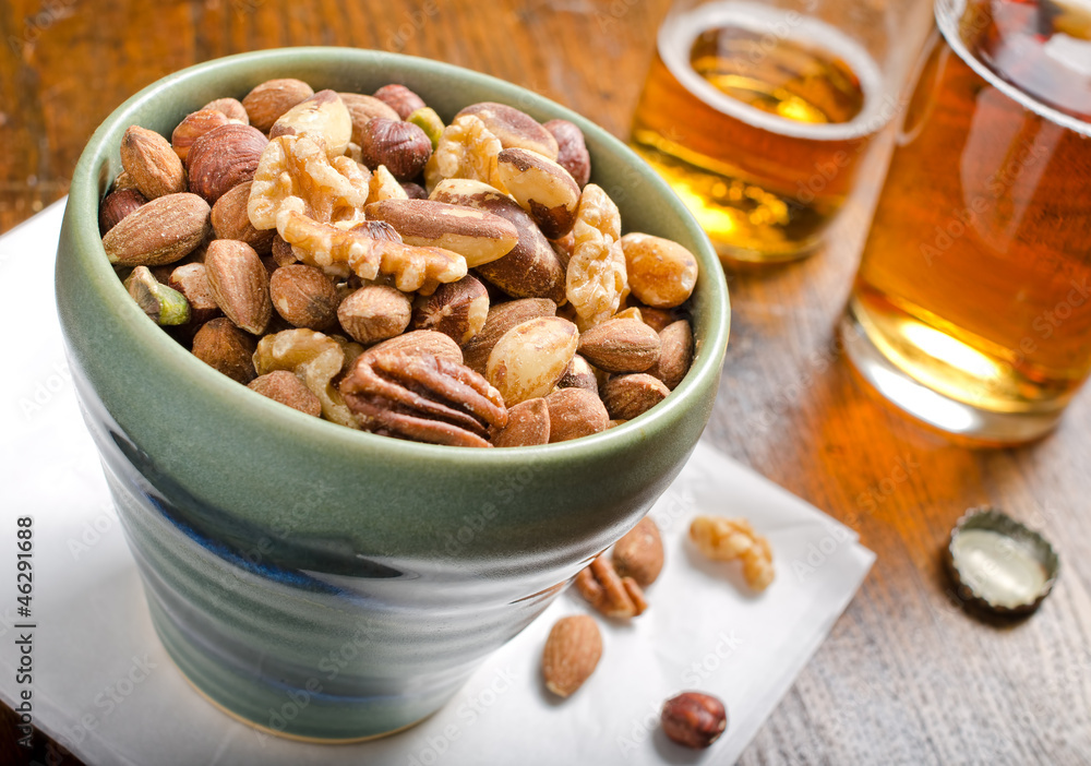 A bowl of mixed nuts and beer.