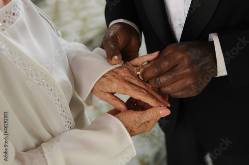 elderly mixed couple exchanging wedding rings