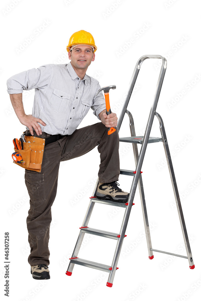 carpenter with leg resting on ladder holding hammer carpenter with leg resting on ladder holding hammer