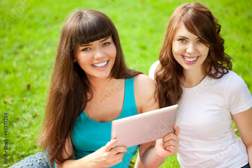 Two women in the park on a picnic with a Tablet PC