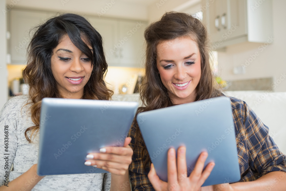 Two smiling women holding and looking at tablet computers Two smiling women holding and looking at tablet computers