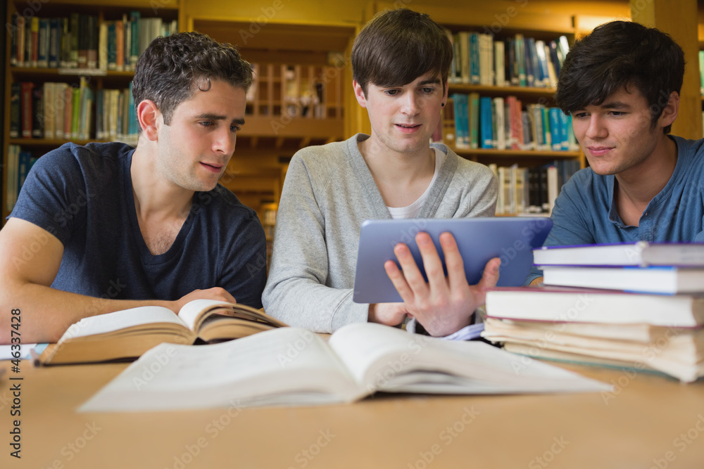 Men sitting at the library looking at tablet pc Men sitting at the library looking at tablet pc