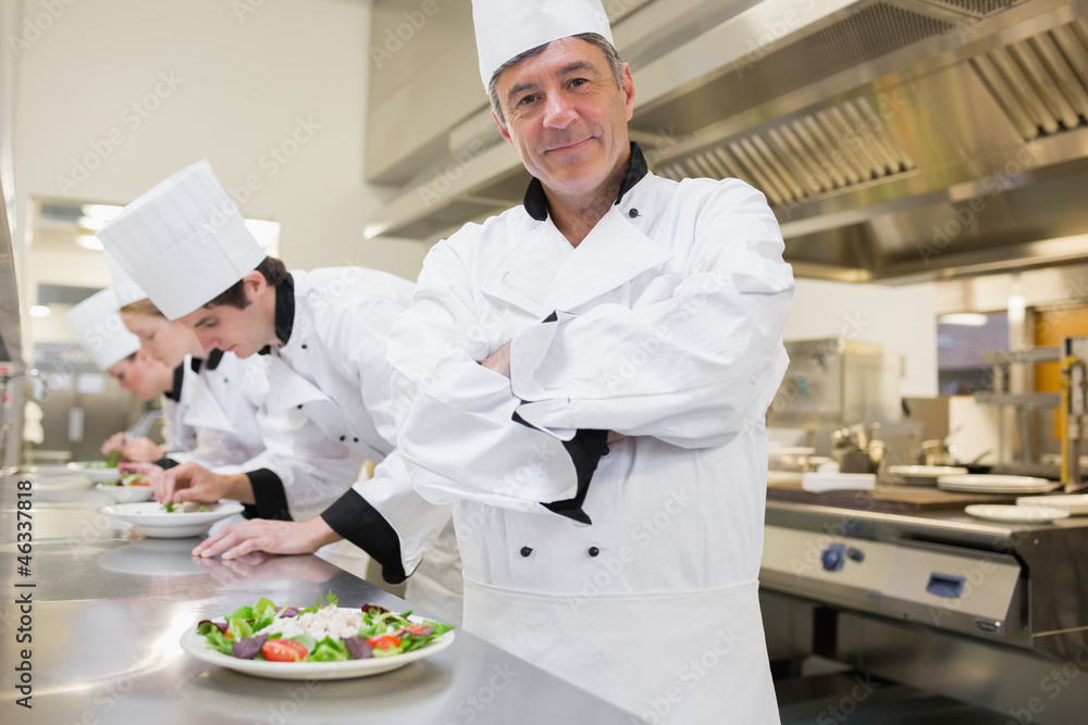 Chef smiling with others preparing salads Chef smiling with others preparing salads