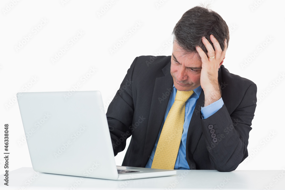 Troubled man sitting at his desk with a laptop Troubled man sitting at his desk with a laptop