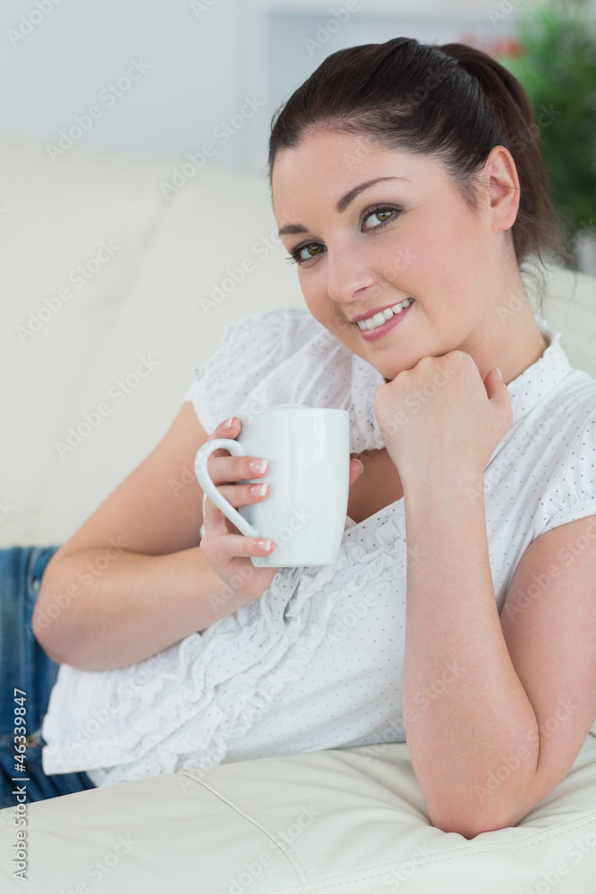 Lying woman on the couch holding a mug