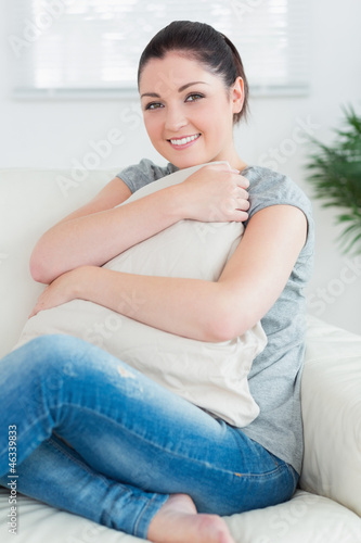 Woman hugging a pillow while sitting on the couch