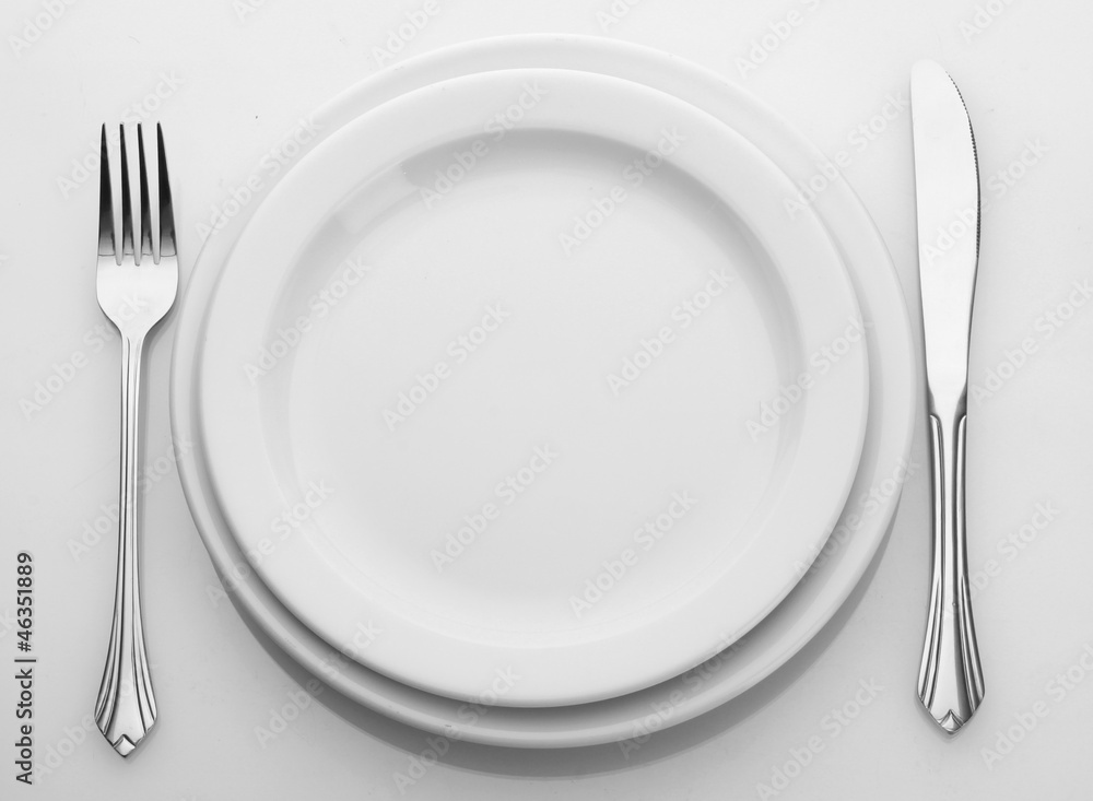 White empty plate with fork and knife isolated on white White empty plate with fork and knife isolated on white