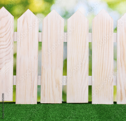 wooden fence and green grass on bright background.