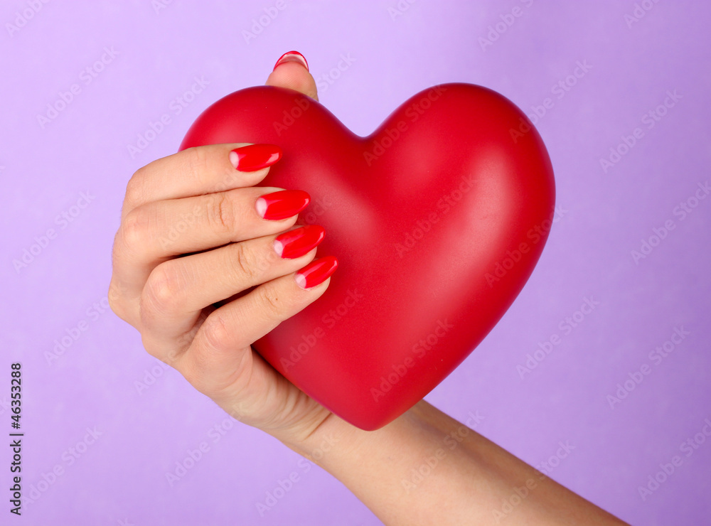 Obraz premium Red heart in woman's hand on color background