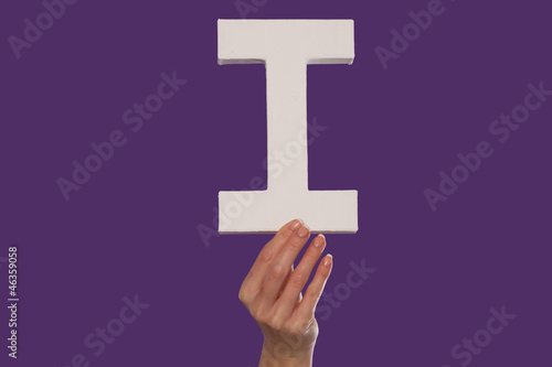 Female hand holding up the letter I from the bottom