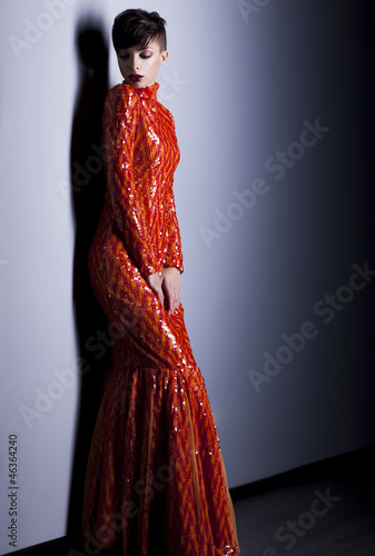 Pretty fashion woman in elegant long red dress posing in studio