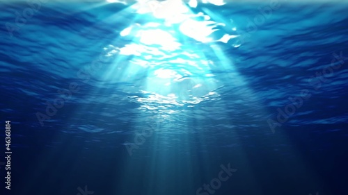 Underwater sunrays shine through the water's surface. Looping.