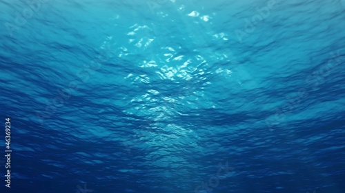 Underwater sunrays shine through the water's surface. Looping.