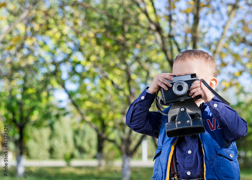 Little boy taking pictures in a park