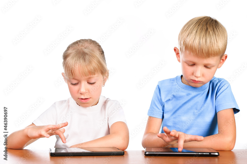 elementary boy and girl sitting at table using digital pads elementary boy and girl sitting at table using digital pads