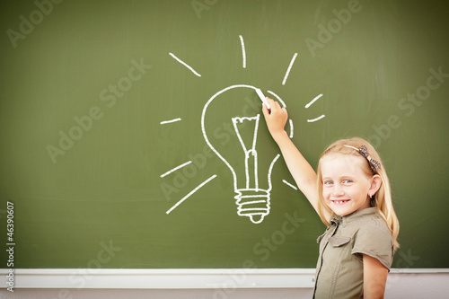 Scoolgirl standing near blackboard photo