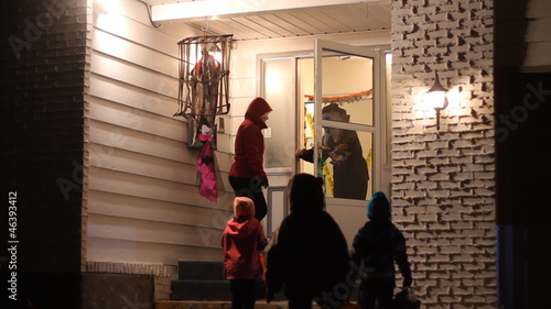 Children with family in Halloween costumes trick or treating