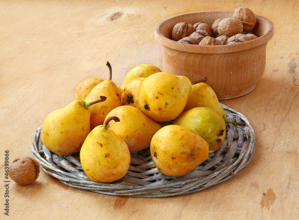 Yellow pears and walnuts on a wooden table
