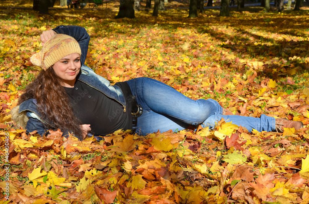 Young woman lying in bright autumn leaves and smiling Young woman lying in bright autumn leaves and smiling