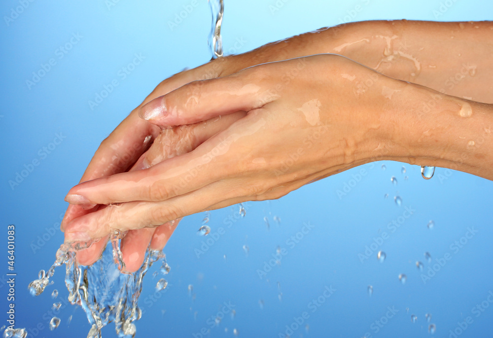 Fototapeta premium Washing hands on blue background close-up