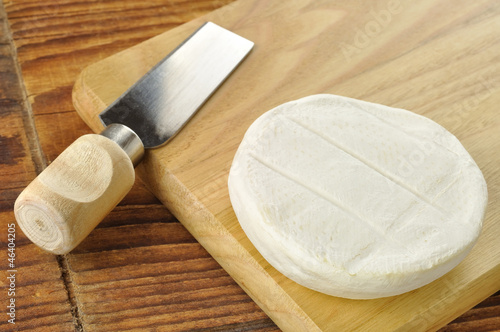 Italian tomino cheese on a wooden chopping board