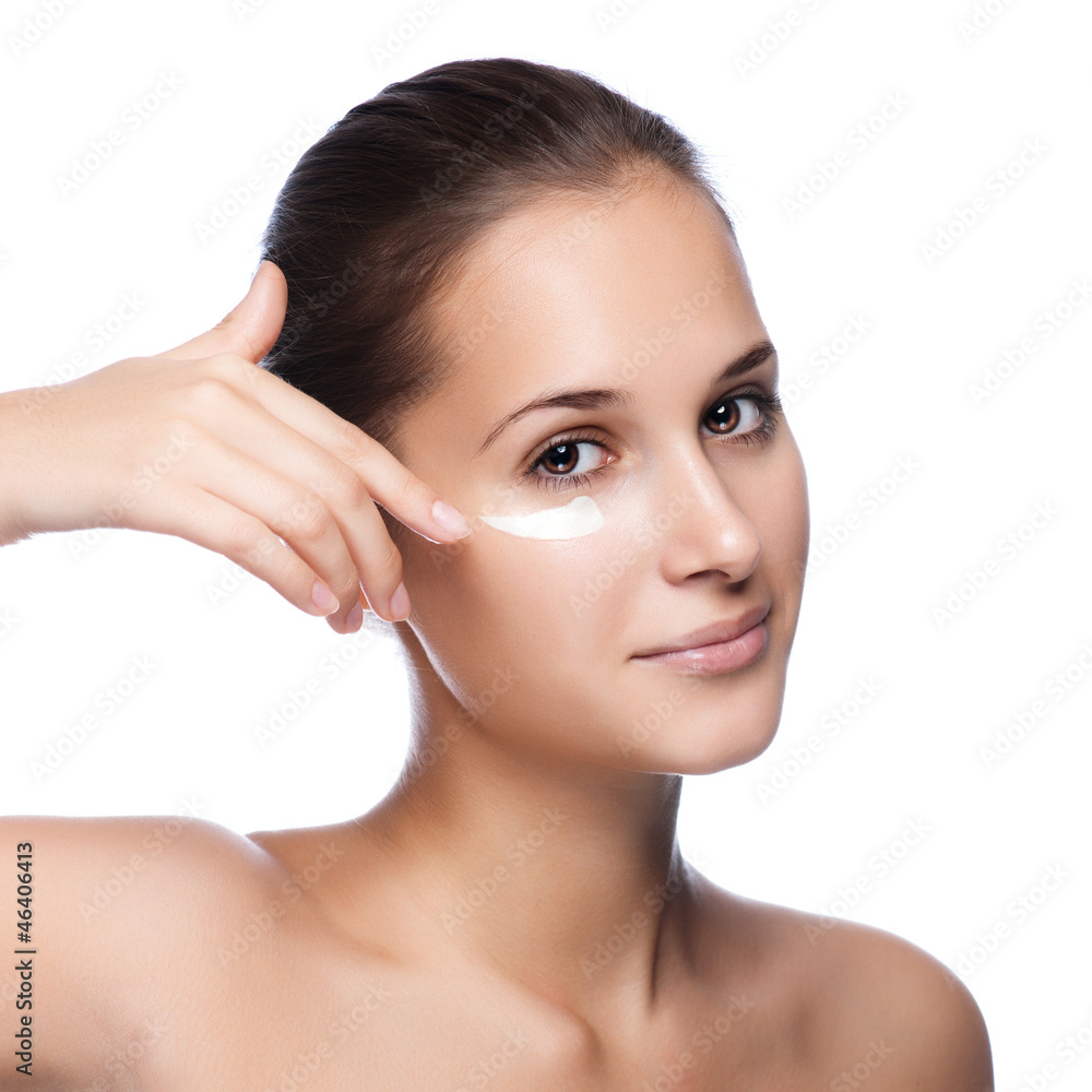 Portrait of beautiful woman applying cream on face - isolated on