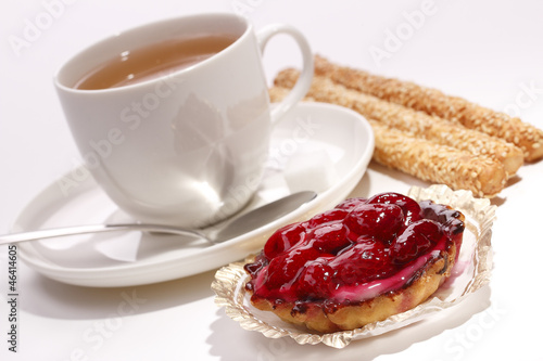 raspberry cake with a cup of tea and biscuits