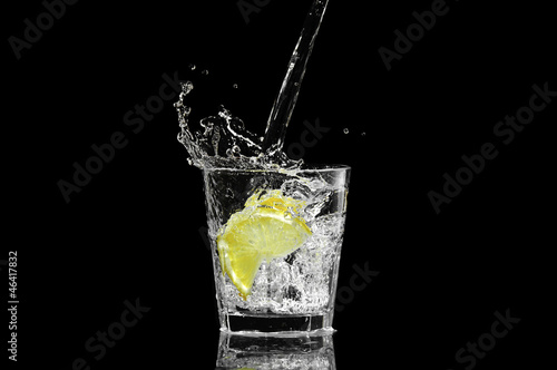 splash in a glass with lemon and ice on a black background
