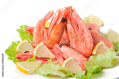 Boiled shrimps with lettuce leaves on plate, isolated on white