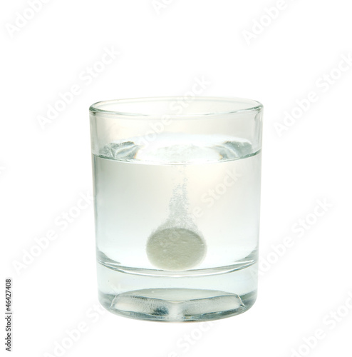 Effervescent tablet splashing into glass isolated on white