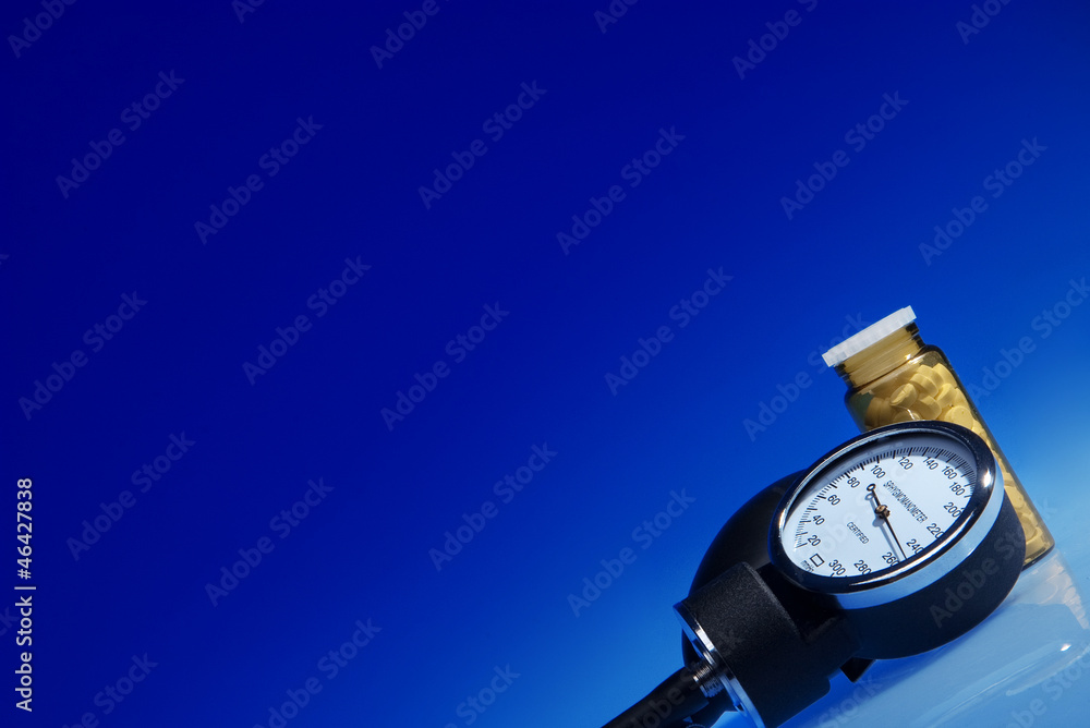 Sphygmomanometer and medicine bottle on blue background Sphygmomanometer and medicine bottle on blue background