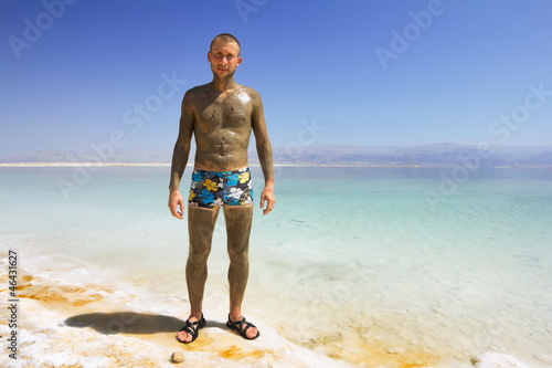 Male in mineral mud is on the shores of the dead sea in Israel