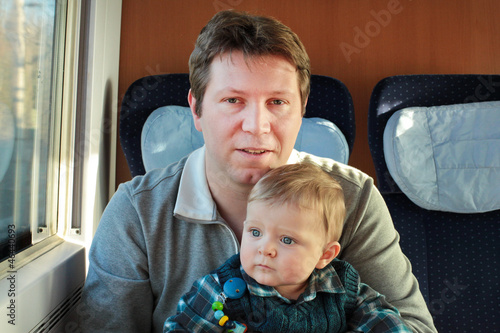 Young father and toddler boy sitting in train