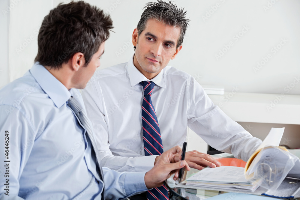 Businessmen Discussing Paperwork In Office Businessmen Discussing Paperwork In Office