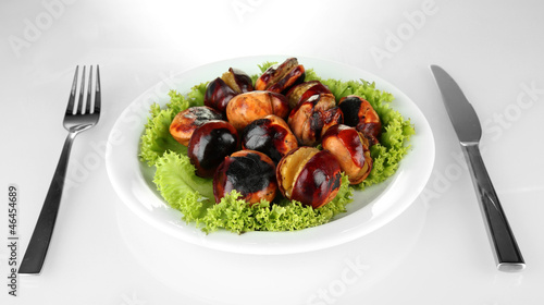 roasted chestnuts with lettuce in the white plate with fork and