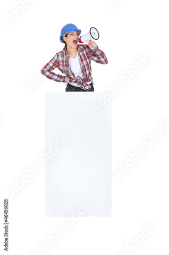 craftswoman shouting through megaphone behind a blank poster © auremar