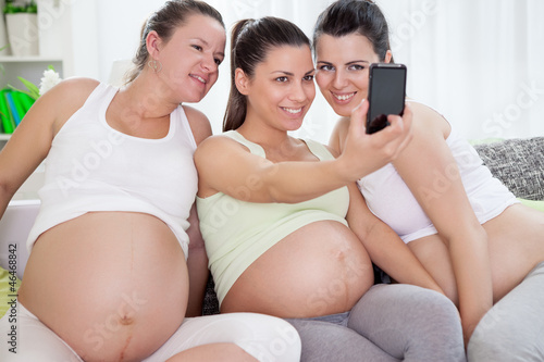 Three pregnant women take photo by mobile phone