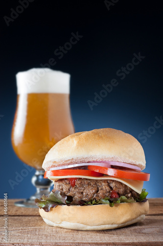 Burger with cheese, onion, tomato and lettuce served with a beer