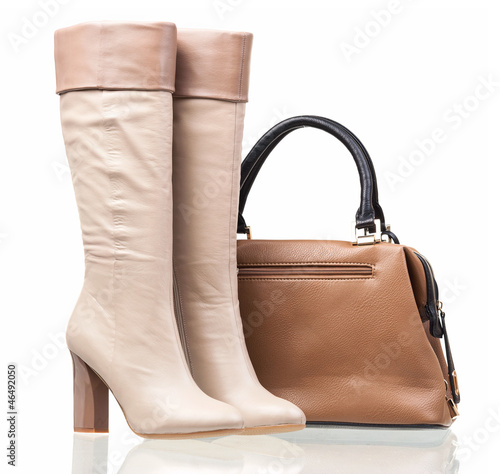 Women high-heeled boots and leather bag over white