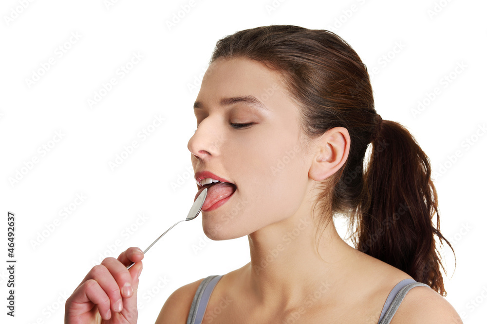 Young smiling woman with spoon in her mouth Young smiling woman with spoon in her mouth