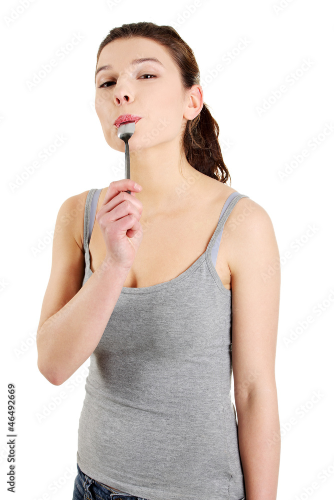 Young smiling woman with spoon in her mouth Young smiling woman with spoon in her mouth