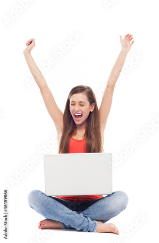 Girl sitting with laptop, arms raised © pikselstock