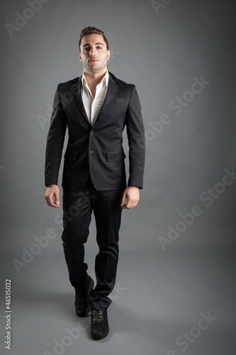 Young man full body portrait against grey background.