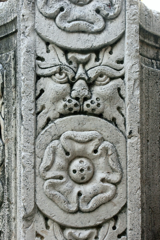 ornate venetian water well in corfu with carved lions head and tudor rose flower