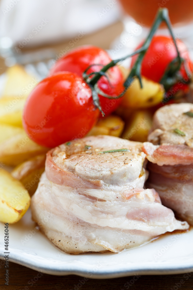 Pork fillet in bacon with cherry tomatoes and baked potato
