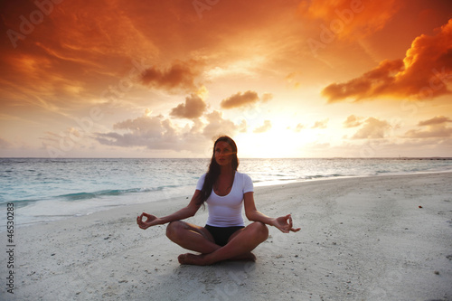 Yoga woman on beach at sunset