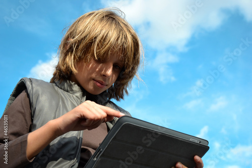 Enfant blond pointant sur tablette numérique photo