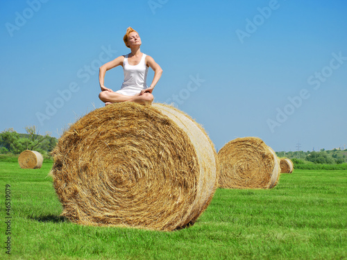 Young woman on the big hay bale roll