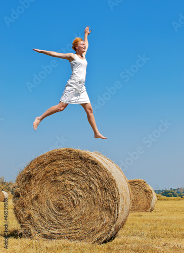 Young woman having fun on the field with big hay bale rolls